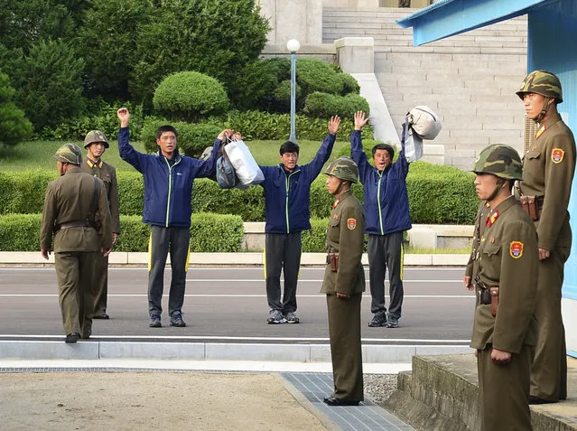 In this photo released by South Korea's Unification Ministry, North Koreans cheer after returning from South Korea at the border village of Panmunjom, South Korea, Friday, July 6, 2013. South Korea repatriated three North Koreans rescued in South Korean waters aboard their drifting boat. (Photo by AP Photo/Unification Ministry)
