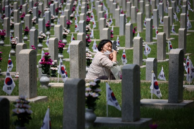 A woman mourns in front of a gravestone of a family member who died for the country, on the eve of Korean Memorial Day at the National Cemetery in Seoul, South Korea on June 5, 2023. (Photo by Kim Hong-Ji/Reuters)