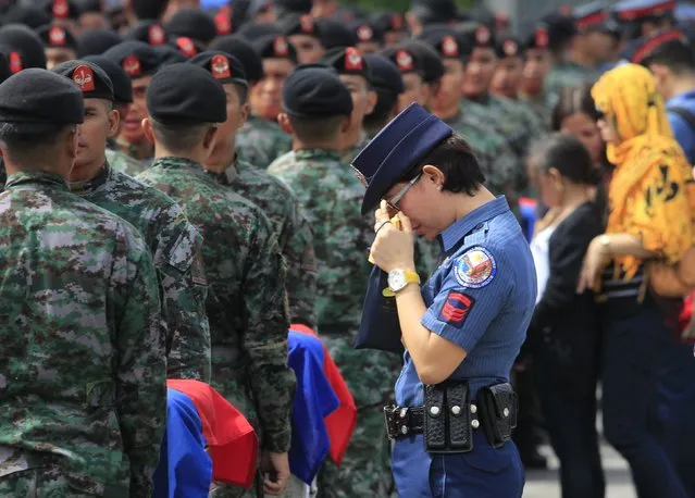 A policewoman wipes her tears as she stands in front of metal caskets containing the bodies of Special Action Force (SAF) police who were killed in Sunday's clash with Muslim rebels, at Villamor Air Base in Pasay city, metro Manila January 29, 2015. (Photo by Romeo Ranoco/Reuters)