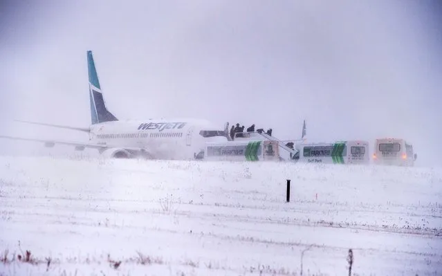 Passengers disembark a Westjet aircraft that skidded off the runway at Halifax Stanfield International Airport on Sunday, January 5, 2020. The airline confirmed Flight 248 was en route from Toronto to Halifax and had landed on Runway 14 when the jet skidded off the end of the runway with 172 passengers and seven crew members aboard. The company said there were no injuries. (Photo by Andrew Vaughan/The Canadian Press via AP Photo)