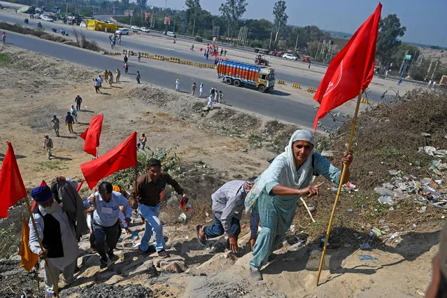 Protesters walk next to a national highway to block KMP Expressway during a roadblock-protest called by farmers,as a part of their continuing demonstration against the central government's recent agricultural reforms, at Kundli in Haryana state on March 6, 2021. (Photo by Prakash Singh/AFP Photo)