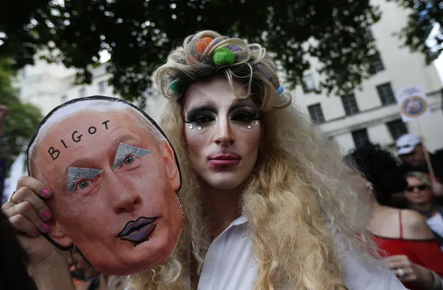 An activist poses with a mask depicting Russian President Vladimir Putin during a protest against Russia's new law on gays, in central London, Saturday, August 10, 2013. Hundreds of protesters, called for the Winter 2014 Olympic Games to be taken away from Sochi, Russia, because of a new Russian law that bans “propaganda of nontraditional sexual relations” and imposes fines on those holding gay pride rallies. (Photo by Lefteris Pitarakis/AP Photo)