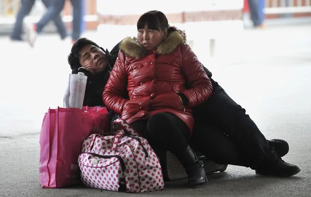 A couple rest on their luggage as they wait to board their train at a railway station in Hefei, Anhui province February 3, 2015. (Photo by Reuters/Stringer)