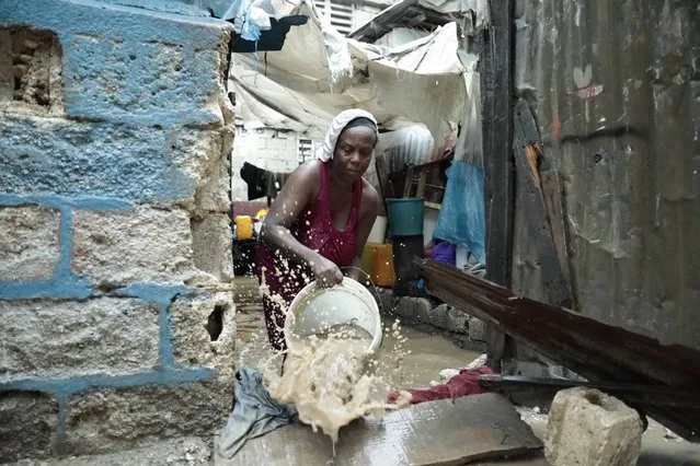 A woman uses a bucket to remove water from inside her flooded house, after a heavy rain in Port-au-Prince, Haiti, Saturday, June 3, 2023. (Photo by Joseph Odelyn/AP Photo)
