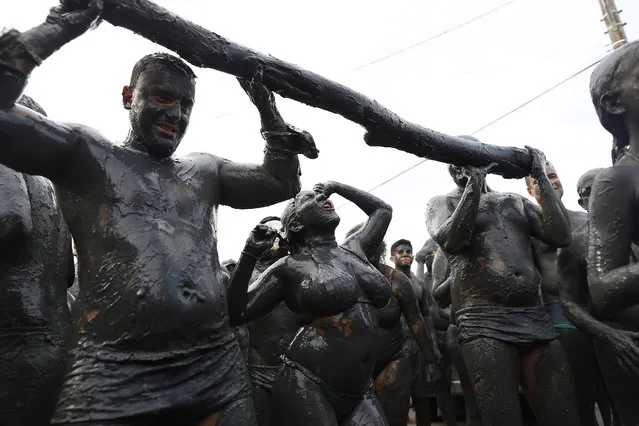 People covered in mud dance during the traditional “Bloco da Lama” or “Mud Block” carnival party, in Paraty, Brazil, Saturday, February 14, 2015. (Photo by Leo Correa/AP Photo)