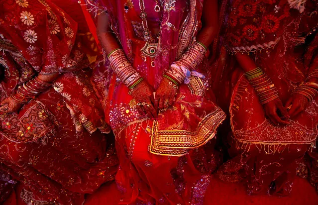Indian brides from impoverished families, dressed in wedding finery, wait for their grooms to arrive during a mass marriage ceremony in New Delhi, India, Friday, February 20, 2015. 12 couples tied the knot in a single ceremony organized by a social organization, that would otherwise have cost each family thousands of dollars. (Photo by Saurabh Das/AP Photo)