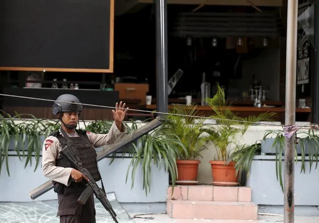 An Indonesian police office walks near a cafe which was damaged following a gun and bomb attack in central Jakarta January 14, 2016. (Photo by Darren Whiteside/Reuters)