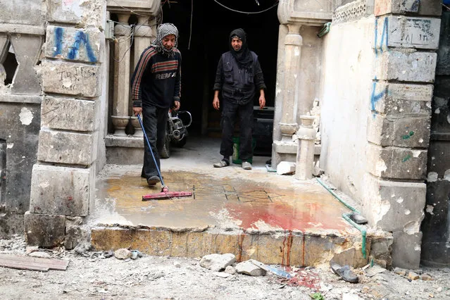 Men wash the blood stained ground after strikes on rebel-held besieged al-Zebdieh district, in Aleppo Syria December 5, 2016. (Photo by Abdalrhman Ismail/Reuters)