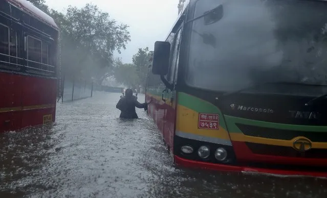 A woman walks through a waterlogged street in Mumbai, India, Monday, May 17, 2021. (Photo by Rafiq Maqbool/AP Photo)