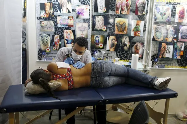 An artist works on a tattoo on a woman during the third International Tattoo Week Rio 2016 festival in Rio de Janeiro, Brazil, January 22, 2016. (Photo by Pilar Olivares/Reuters)