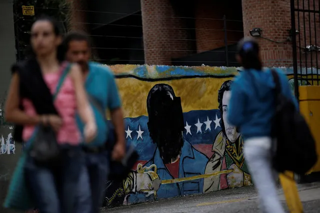 Venezuelan citizens walk past a mural depicting former Venezuela's late President Hugo Chavez, with his head painted in black ink, in Caracas, Venezuela December 2, 2016. (Photo by Ueslei Marcelino/Reuters)