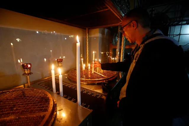 A visitor lights a candle inside the Church of the Nativity in the West Bank town of Bethlehem December 23, 2016. (Photo by Mussa Qawasma/Reuters)