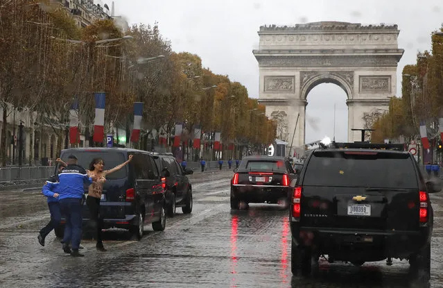 French police officers apprehend a topless protestor who ran toward the motorcade of President Donald Trump who was headed on the Champs Elysees to an Armistice Day Centennial Commemoration at the Arc de Triomphe, Sunday November 11, 2018, in Paris. Trump is joining other world leaders at centennial commemorations in Paris this weekend to mark the end of World War I. (Photo by Jacquelyn Martin/AP Photo)