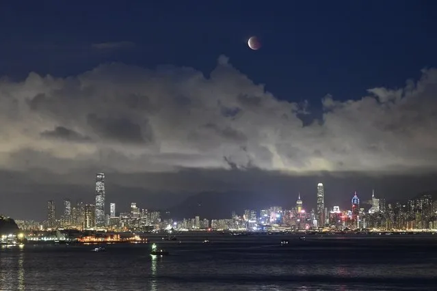 The moon rises over the Victoria Harbour in Hong Kong, Wednesday, May 26, 2021. The first total lunar eclipse in more than two years coincides with a supermoon this week for quite a cosmic show. (Photo by Kin Cheung/AP Photo)