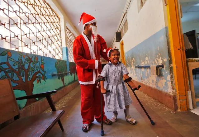 A person dressed in a Santa Claus costume interacts with a physically challenged child during a Christmas celebrations at a municipal school in Mumbai, India, December 20, 2016. (Photo by Shailesh Andrade/Reuters)
