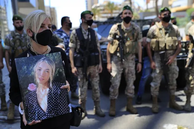 A woman holds a portrait of a victim who killed during the last year's massive blast at Beirut's seaport, protest near the tightly-secured residents of parliament speaker Nabih Berri, in Beirut, Lebanon, Friday, July 9, 2021. The protest came after last week's decision by the judge to pursue senior politicians and former and current security chiefs in the case, and requested permission for their prosecution. (Photo by Hussein Malla/AP Photo)
