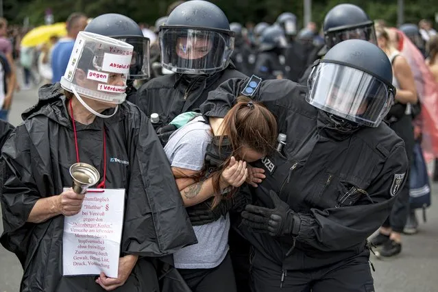 Police arrest a demonstrator at an unannounced demonstration at the Victory Column, in Berlin, Sunday August 1, 2021, during a protest against coronavirus restrictions. Hundreds have turned out in Berlin to protest the German government’s anti-coronavirus measures despite a ban on the gatherings, leading to arrests and clashes with police. (Photo by Fabian Sommer/dpa via AP Photo)