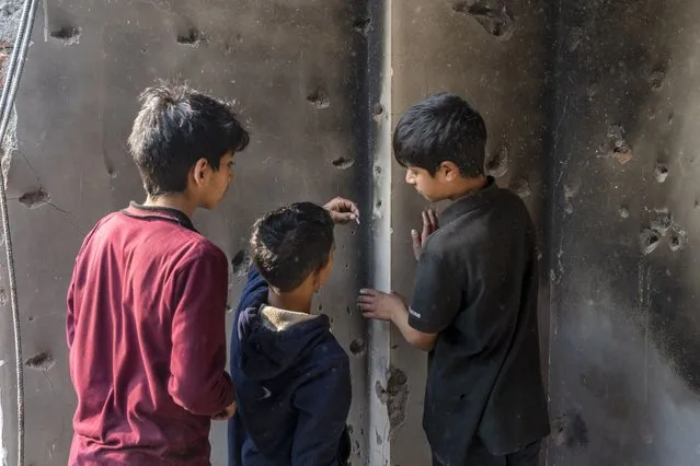 A Kashmiri boy, center, takes out a bullet from the wall of a damaged house after a gunbattle in Kulgam south of Srinagar, Indian controlled Kashmir, Friday, November 17, 2023. Police in Indian-controlled Kashmir said government forces killed five suspected militants in a gunbattle on Thursday. (Photo by Dar Yasin/AP Photo)
