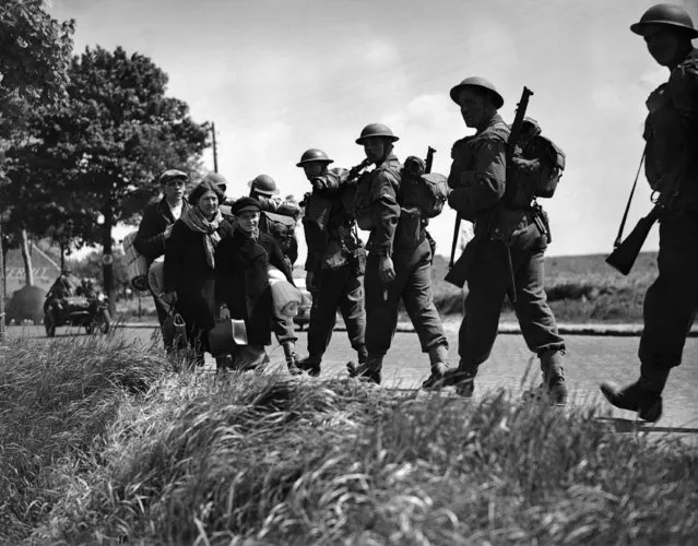 On a Belgian road, Belgian refugees, carrying all that they have been able to pack of their possessions, fleeing before the German invasion of their country. British soldiers, going forward in Belgium, passing refugees on May 17, 1940. (Photo by AP Photo)