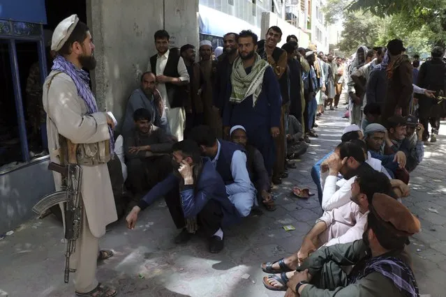 Afghans wait in front of Kabul Bank, in Kabul, Afghanistan, Wednesday, August 25, 2021. The Taliban wrested back control of Afghanistan nearly 20 years after they were ousted in a U.S.-led invasion following the 9/11 attacks. Their return to power has pushed many Afghans to flee, fearing reprisals from the fighters or a return to the brutal rule they imposed when they last ran the country. (Photo by AP Photo/Stringer)
