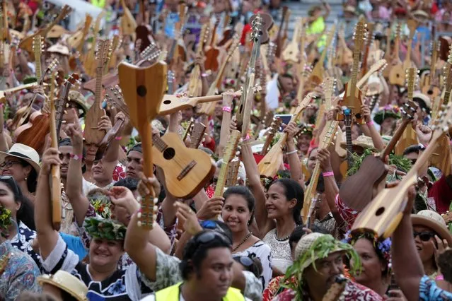 People try on April 11, 2015 to beat the world record of ukelele players at the first Tahiti Ukulele Festival in Papeete with more than 4,750 participants from all the islands of the French Indian Ocean archipelago. The largest ukulele ensemble was set in July 2014 with 2,370 participants in Southampton. (Photo by Gregory Boissy/AFP Photo)