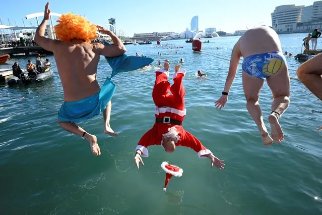 Participants in fancy costumes jump into the water during the 114th edition of the Copa Nadal (Christmas Cup) swimming race in Barcelona's Port Vell on December 25, 2023. The traditional 200-meter Christmas swimming race gathered around 300 participants on Barcelona's Port Vell (old harbour). (Photo by Josep Lago/AFP Photo)
