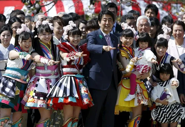 Japan's Prime Minister Shinzo Abe (C) poses with members of Japanese idol group Momoiro Clover Z and other show-business celebrities at a cherry blossom viewing party at Shinjuku Gyoen park in Tokyo April 18, 2015. (Photo by Issei Kato/Reuters)