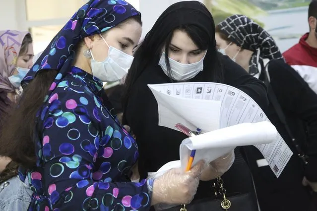 Chechen women read their ballots a polling station during the Parliamentary elections in Grozny, Russia, Saturday, September 18, 2021. (Photo by Musa Sadulayev/AP Photo)