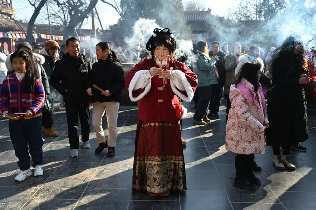 A woman in traditional clothes offers prayers at the Lama Temple on the first day of the Lunar New Year of the Dragon in Beijing on February 10, 2024. (Photo by Greg Baker/AFP Photo)
