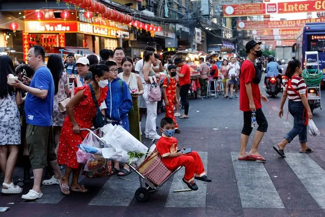 A boy is carried in a cart as people walk on the street in Chinatown during the Lunar New Year's Eve in Bangkok, Thailand, on February 9, 2024. (Photo by Jorge Silva/Reuters)