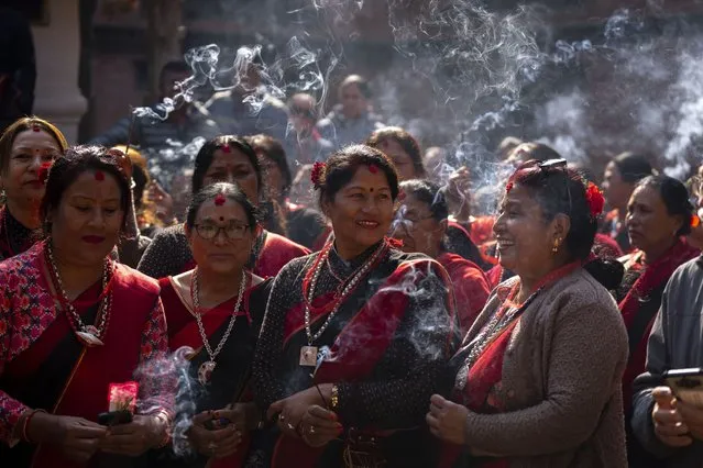 Women in traditional attire light incense sticks as a 16th century statue of Hindu deity Uma-Maheswora, that was stolen four decades ago and later repatriated is paraded before reinstating the same at the premises of a temple where it belonged in Lalitpur, Nepal, Thursday, February 15, 2024. The idol had somehow ended up at the Brooklyn Museum in New York, which handed over the same to the Manhattan District Attorney's Office paving way to its return to Nepal. (Photo by Niranjan Shrestha/AP Photo)