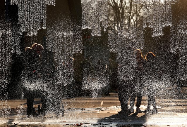People enjoy the fountain 'Digital water curtain' in Ogre, Latvia, 31 October 2021. Four meters wide and almost three meters high, the digital fountain is made of separate falling water jets and decorated with bronze plates. (Photo by Toms Kalnins/EPA/EFE/Rex Features/Shutterstock)