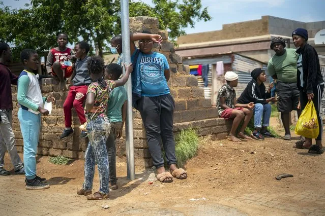 Residents stand in the streets of Lawley, South Africa, during a visit of local government officials for the launch of the Vooma vaccination program against COVID-19 Friday December 3, 2021. South Africa has accelerated its vaccination campaign a week after the discovery of the omicron variant of the coronavirus. (Photo by Jerome Delay/AP Photo)
