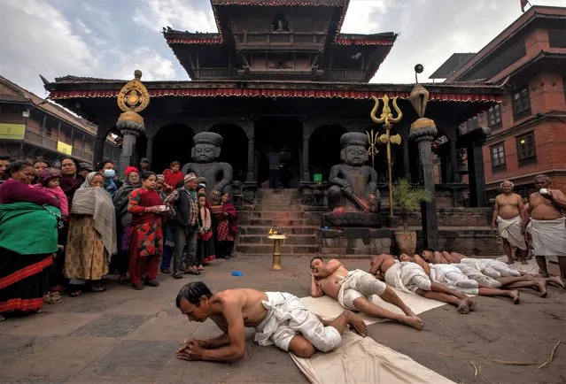 Nepalese Hindu devotees roll on the ground during the month long Madhav Narayan festival in Bhaktapur, Nepal, 26 January 2023. The Madhav Narayan festival takes place for a full month and is devoted to religious fasting, holy bathing and the study of the Swasthani book, a chapter or story of which is read each evening by priests or heads of households to the gathered family. Thousands of married women and dozens of male devotees concluded their month-long fast for a better life and peace in the country at various temples. According the Swasthani book, whoever takes the month long Swasthani fast, all their sins will be forgiven and they will not experience bad days during their life. The festival is dedicated to Lord Shiva, the god of creation and destruction. (Photo by Narendra Shrestha/EPA/EFE)