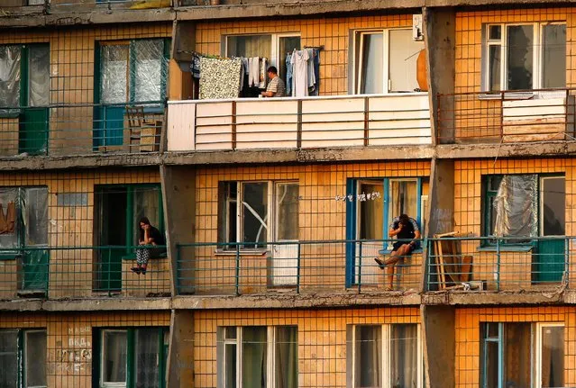 Residents are seen at sunset on their balconies of an apartment building in central Donetsk, March 24, 2014. Donetsk is a city of almost one million inhabitants and was founded in 1869 when Welsh businessman John Hughes built a steel plant and several coal mines in the area. (Photo by Yannis Behrakis/Reuters)