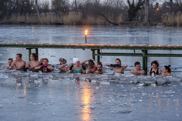 Members of the “Cold Water Tribe” group take a late dip in an ice hole that they broke into a frozen lake in Veresegyhaz, Hungary, 14 February 2021. The members of the group are fans of cold water bathing and gather for a dip in the icy waters of of the region's lakes, ponds or rivers every week during the winter season. (Photo by Peter Lakatos/EPA/EFE)