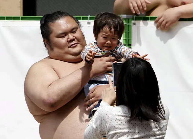 A sumo wrestler poses with a child for pictures during the annual “Honozumo” ceremonial sumo tournament dedicated to the Yasukuni Shrine in Tokyo, Japan, April 18, 2016. (Photo by Yuya Shino/Reuters)