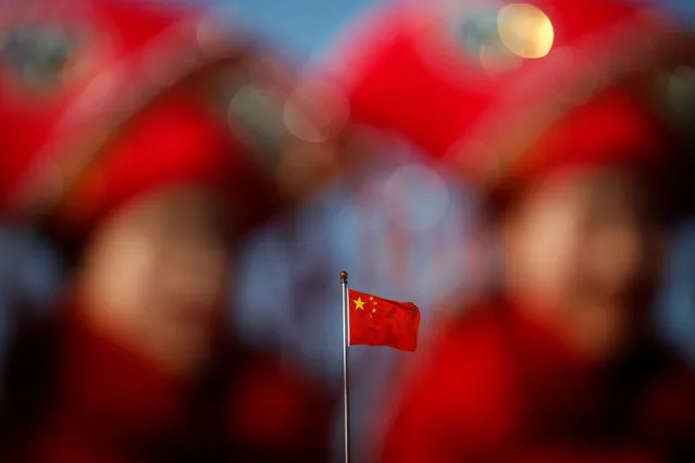 China's national flag is seen behind hostesses waiting for delegates outside the Great Hall of the People during the second plenary session of the National People's Congress (NPC) in Beijing, China March 8, 2017. (Photo by Damir Sagolj/Reuters)