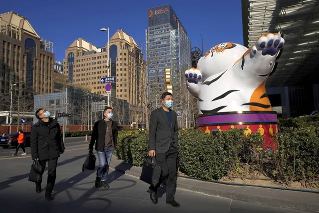 People wearing face masks walk by a gestured tiger statue, a Chinese zodiac which marks the year 2022, on display at the Central Business District in Beijing, Monday, January 17, 2022. China’s economy expanded by 8.1% in 2021 but Beijing faces pressure to shore up activity after an abrupt slump in the second half as the ruling Communist Party forced its vast real estate industry to cut surging debt. (Photo by Andy Wong/AP Photo)
