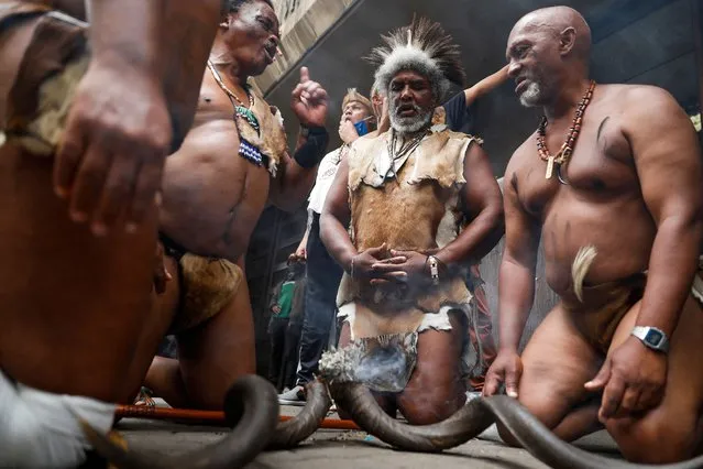 Supporters of King Khoisan South Africa burn incense and chant slogans outside the Pretoria Magistrates Court while waiting for his release from police custody following his arrest for planting marijuana at the Union Buildings in Pretoria on January 13, 2022. King Khaoisan has been camping with his family outside the seat of government for over three years, fighting for the official recognition of their languages and to negotiate land ownership. (Photo by Phill Magakoe/AFP Photo)