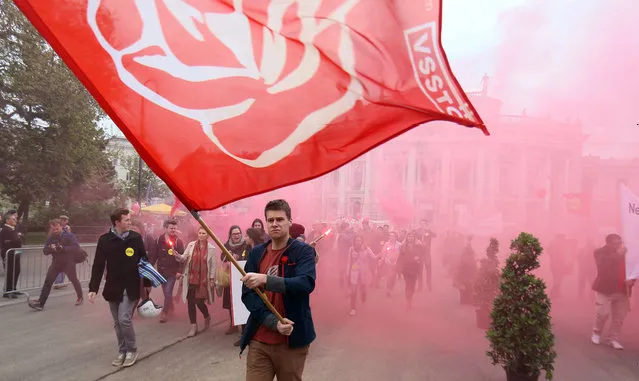 Participants of the traditional May Day celebrations, organized by the Austrian Social Democrats, SPOE, and trade unions walk with a flag in Vienna, Austria, on Sunday, May 1, 2016. Every year around hundred thousand citizens participate the event. (Photo by Ronald Zak/AP Photo)