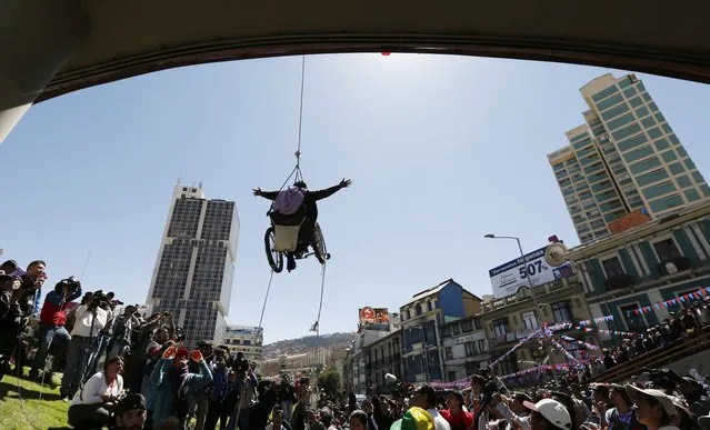 A woman in a wheelchair hangs from a rope under a footbridge in downtown La Paz, Bolivia, Tuesday, May 3, 2016. The demonstration called attention to a group of disabled people demanding an increase in state benefits for those with disabilities, to 500 Bolivianos, or about $73 dollars, per month. The demonstrators began their march by foot to the capital, leaving Cochabamba on March 21. (Photo by Juan Karita/AP Photo)