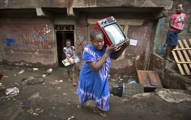 A woman leaves with her television set, as she and others are evicted from their apartment blocks close to the site of last week's building collapse, after their homes were deemed unfit for habitation and marked for demolition, in the Huruma neighborhood of Nairobi, Kenya Friday, May 6, 2016. (Photo by Ben Curtis/AP Photo)