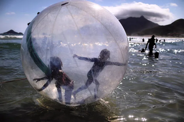 Children try to balance inside a ball at the Macumba beach in Rio de Janeiro, Brazil on February 13, 2022. (Photo by Pilar Olivares/Reuters)
