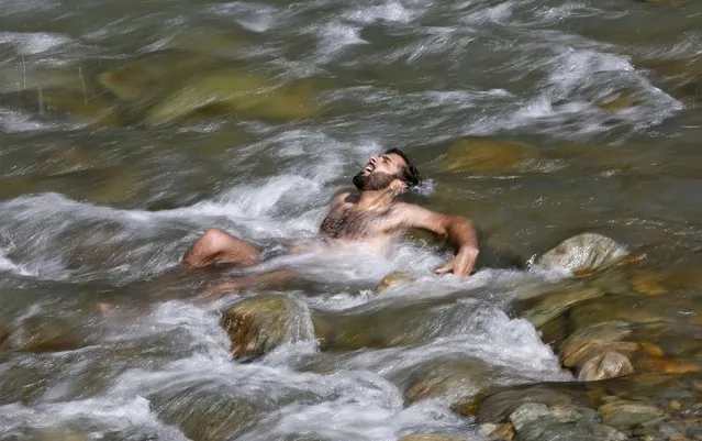 A man bathes in a stream to cool off on the outskirts of Srinagar May 2, 2016. (Photo by Danish Ismail/Reuters)