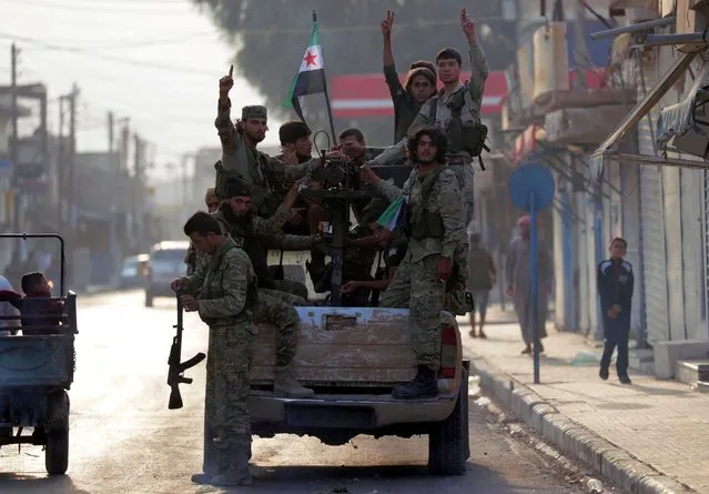 Turkey-backed Syrian rebel fighters gesture as they stand at a back of a truck in the border town of Tal Abyad, Syria, October 17, 2019. (Photo by Khalil Ashawi/Reuters)