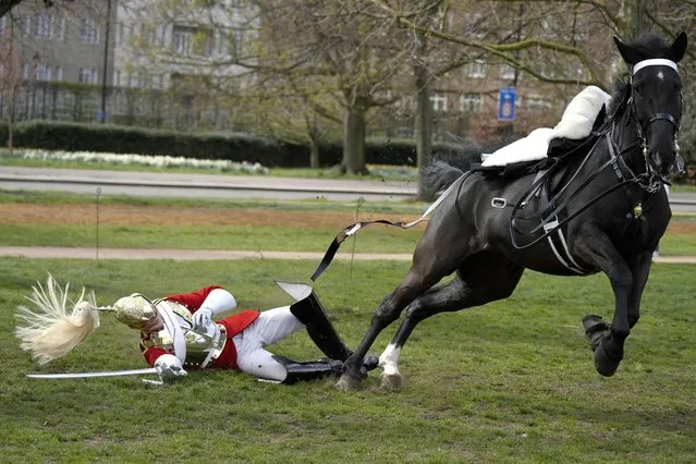 A soldier of the Household Cavalry Mounted Regiment falls off a horse during a practice to participate in the state ceremonial surrounding this year's Platinum Jubilee celebrations at Hyde Park in London, Thursday, March 31, 2022. Around 170 horses and personnel of the Household Cavalry Mounted Regiment left their Hyde Park Barracks to form up and be inspected by the General Officer Commanding the Household Division, Major General Christopher Ghika. (Photo by Frank Augstein/AP Photo)