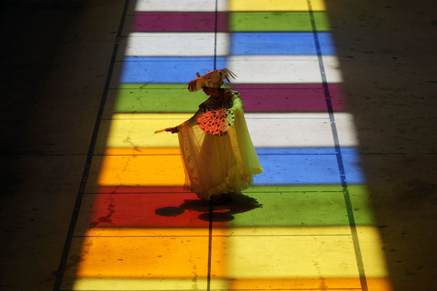 Catherine Cisneros performs across the lighted squares of Christopher Janey's “Passing Light” solar sculpture at San Antonio International Airport, Thursday, June 20, 2024, in San Antonio. The sculpture incorporates large plexiglass squares embedded in the ceiling that project a grid of colors that align with a painted grid for less than a minute each Summer Solstice. (Photo by Eric Gay/AP Photo)