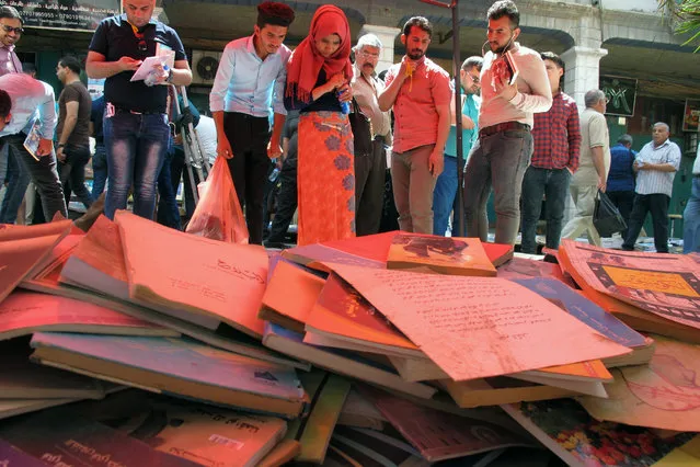 Iraqis buy books at an open-air market in the capital Baghdad's Mutanabi Street on May 5, 2017, to donate them to the University of Mosul's library, as part of an initiative to replenish the institution after its documents were destroyed by Islamic State (IS) group fighters when they took the city. (Photo by Sabah Arar/AFP Photo)