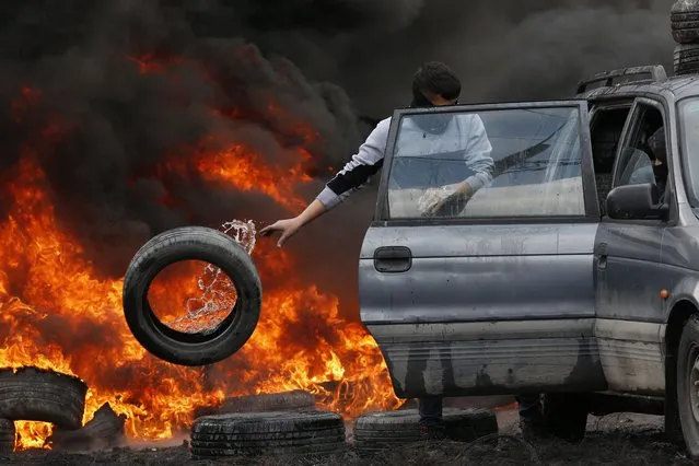 A Palestinian protester burns tires during clashes after a demonstration against Israel's settlements on the lands of Kafr Qadoum village near the West Bank city of Nablus, 25 March 2022. (Photo by Alaa Badarneh/EPA/EFE)
